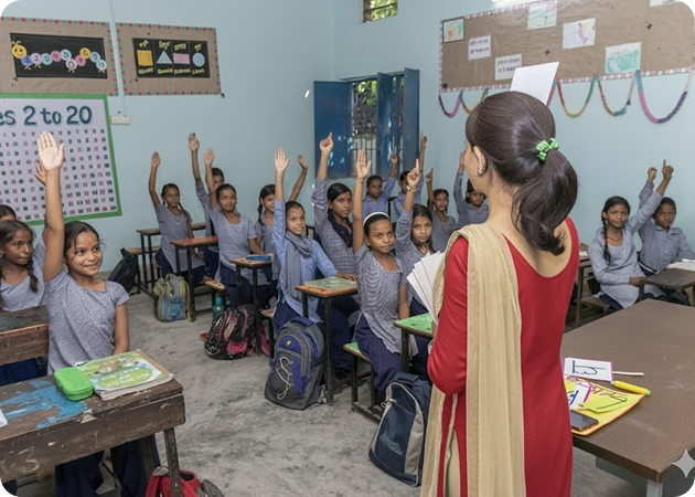 Teacher in a classroom with students raising their hands